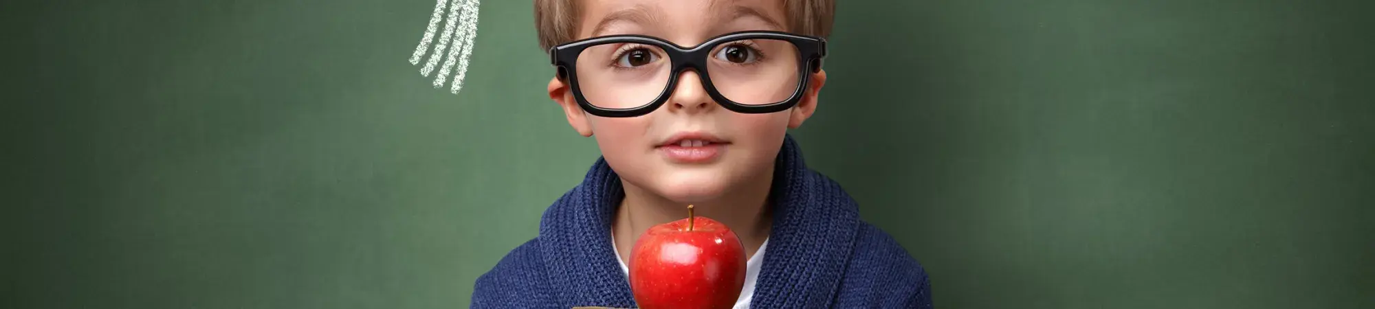 child holding books and apple by a chalkboard