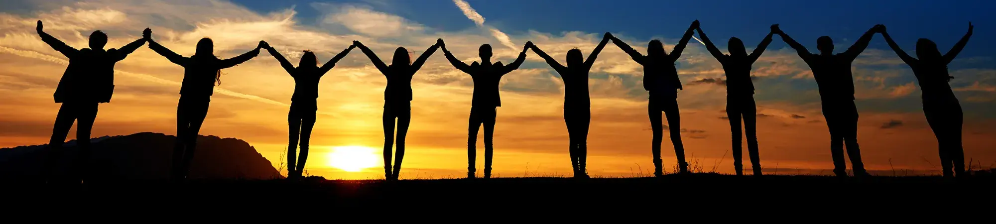 people silhouettes standing hand in hand with sunsetting